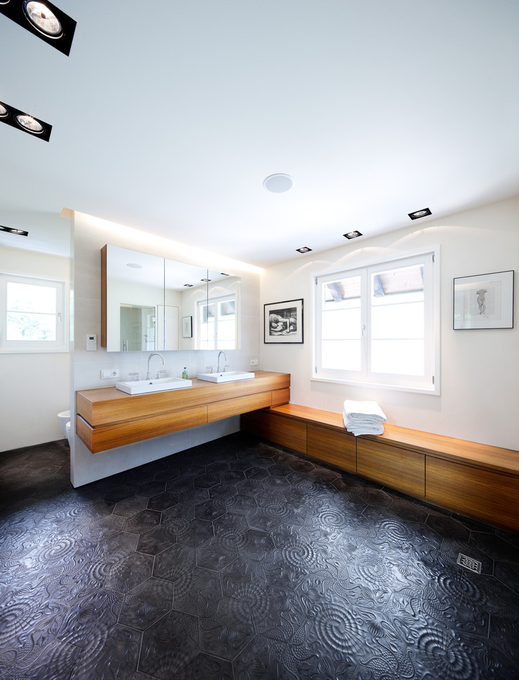Expansive contemporary bathroom in Frankfurt with flat-panel cabinets, medium wood cabinets, white tile, beige walls, a vessel sink, wood benchtops and brown benchtops.