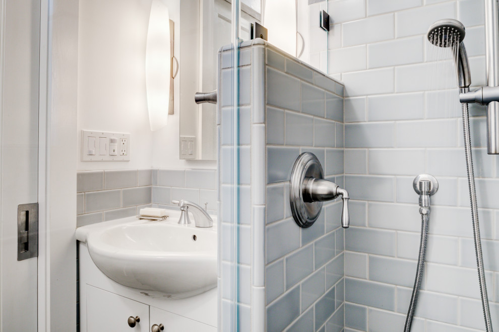 Foto på ett litet vintage vit badrum, med släta luckor, vita skåp, en kantlös dusch, en vägghängd toalettstol, blå kakel, keramikplattor, vita väggar, klinkergolv i porslin, ett integrerad handfat, bänkskiva i akrylsten, blått golv och med dusch som är öppen