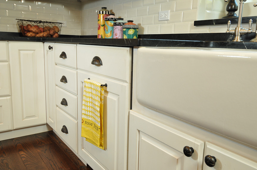 Example of a mountain style l-shaped eat-in kitchen design in Chicago with a farmhouse sink, raised-panel cabinets, white cabinets, soapstone countertops, white backsplash, subway tile backsplash and paneled appliances