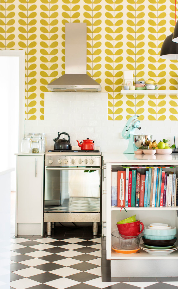 This is an example of an eclectic kitchen in Newcastle - Maitland with flat-panel cabinets, white cabinets, stainless steel appliances, multi-coloured floor and white benchtop.