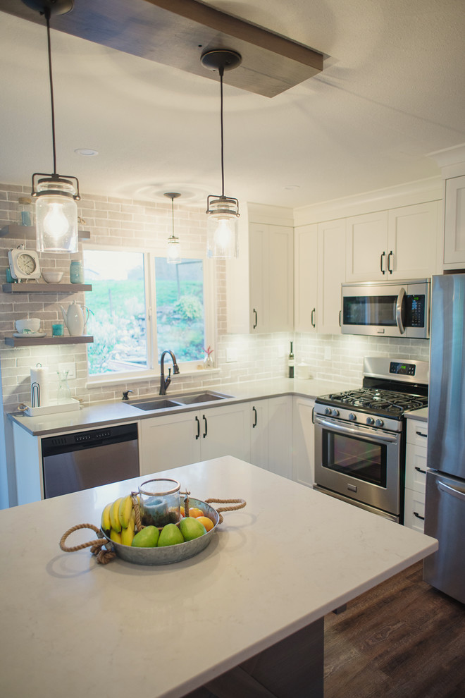 Mid-sized transitional l-shaped open concept kitchen photo in Vancouver with an undermount sink, shaker cabinets, white cabinets, quartz countertops, gray backsplash, stainless steel appliances and an island