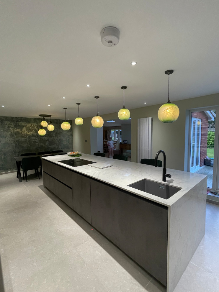 Inspiration for a large contemporary galley kitchen in Manchester with flat-panel cabinets, grey cabinets, quartzite benchtops, grey splashback, stainless steel appliances, porcelain floors, with island, grey floor, grey benchtop and recessed.