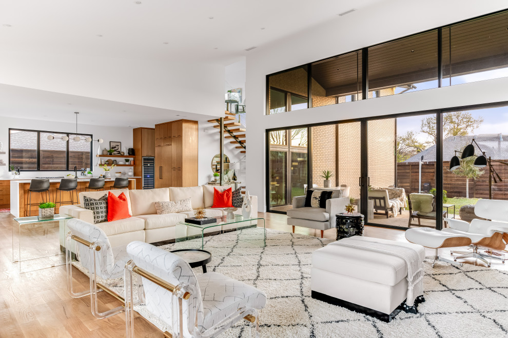 This is an example of a large midcentury open concept living room in Dallas with white walls, light hardwood floors, a standard fireplace, a tile fireplace surround, brown floor and vaulted.