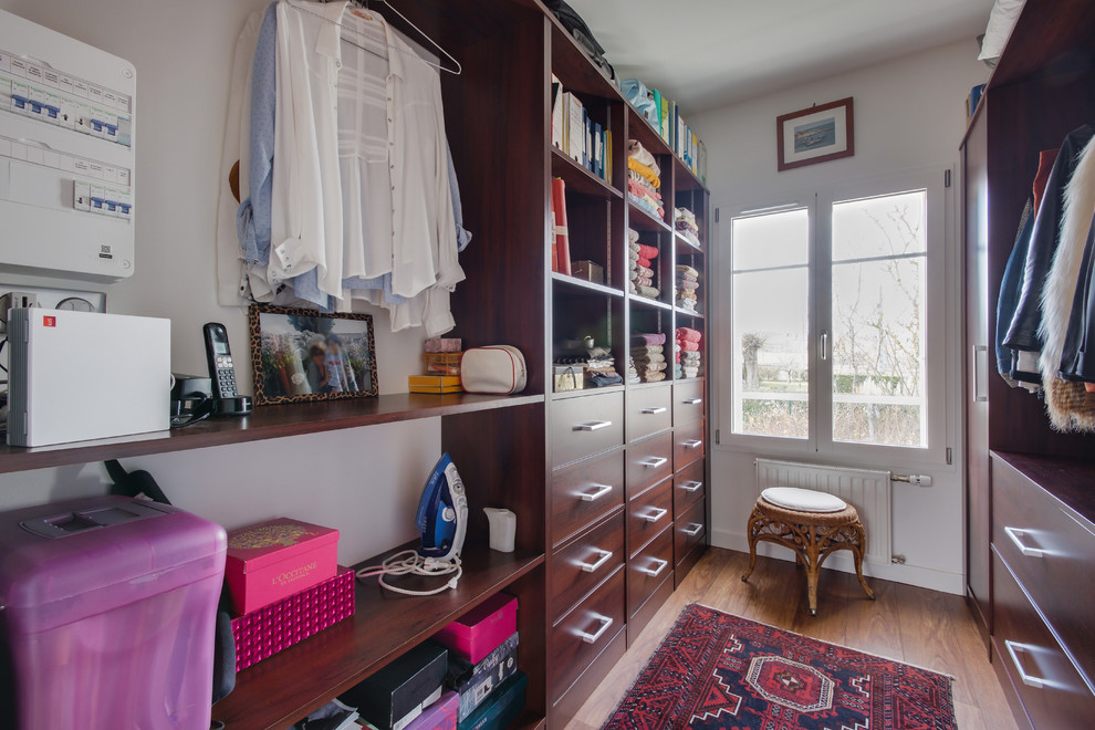 Inspiration for a small contemporary women's dressing room in Clermont-Ferrand with open cabinets, medium wood cabinets, laminate floors and brown floor.