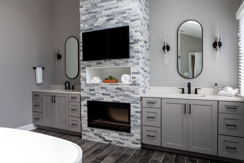 Photo of a large modern master bathroom in Philadelphia with recessed-panel cabinets, grey cabinets, a freestanding tub, a corner shower, a two-piece toilet, grey walls, porcelain floors, an undermount sink, quartzite benchtops, grey floor, a hinged shower door, white benchtops, a shower seat, a double vanity, a built-in vanity and vaulted.