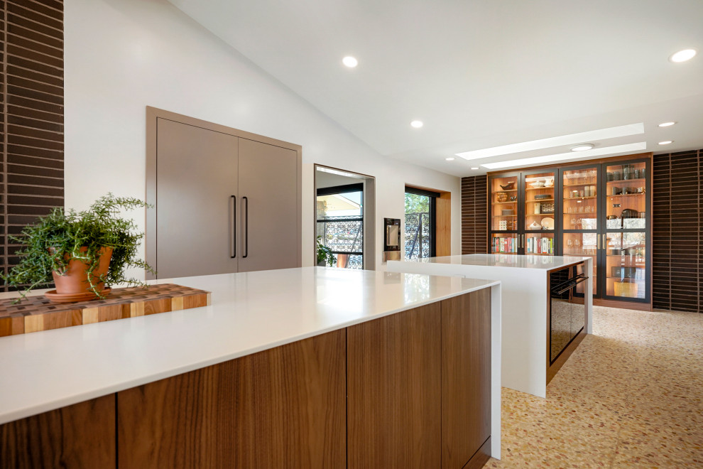 Expansive midcentury single-wall kitchen pantry in Denver with an integrated sink, flat-panel cabinets, medium wood cabinets, quartz benchtops, white splashback, panelled appliances, multiple islands, white benchtop and exposed beam.