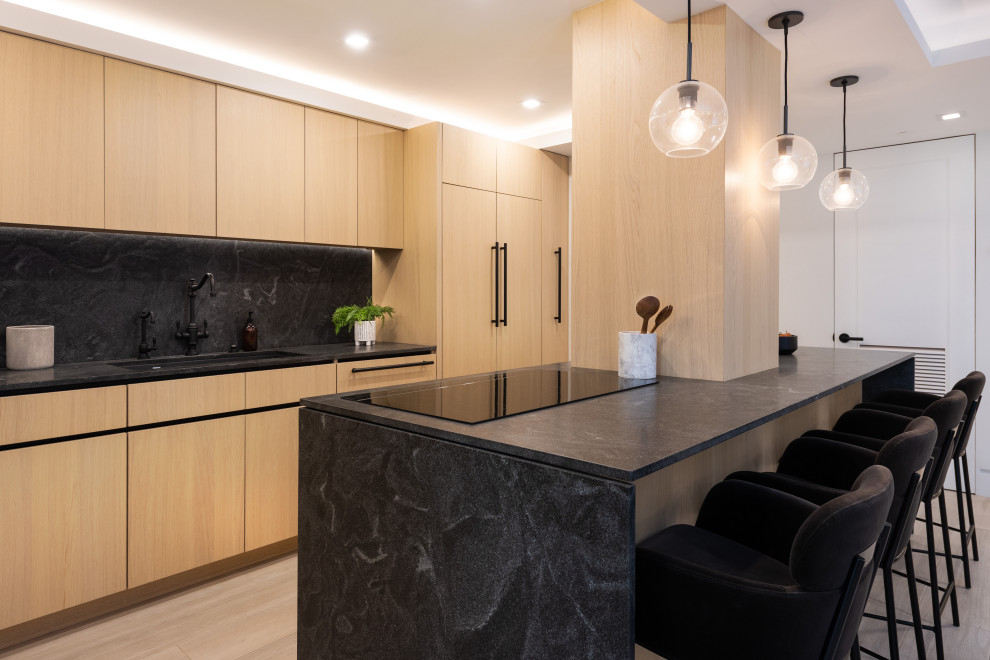 This is an example of a medium sized modern l-shaped open plan kitchen in San Diego with a single-bowl sink, flat-panel cabinets, light wood cabinets, granite worktops, integrated appliances, porcelain flooring, an island and black worktops.