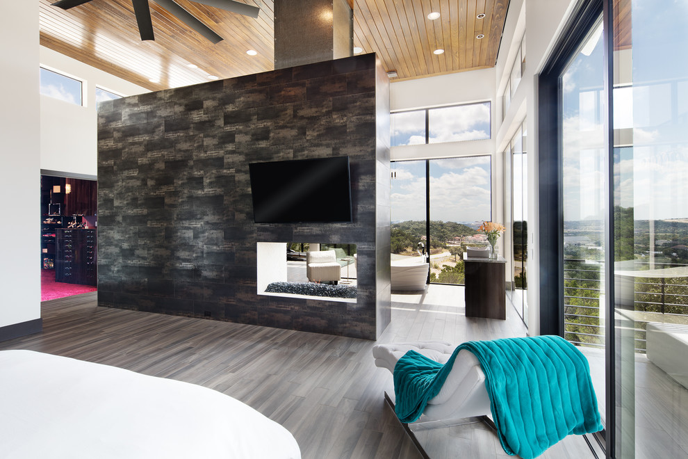 This is an example of a large modern master bedroom in Austin with multi-coloured walls, porcelain floors, a two-sided fireplace and a tile fireplace surround.