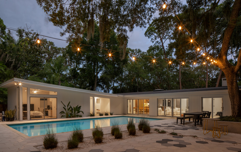 This is an example of a large retro back rectangular lengths swimming pool in Tampa with concrete paving.