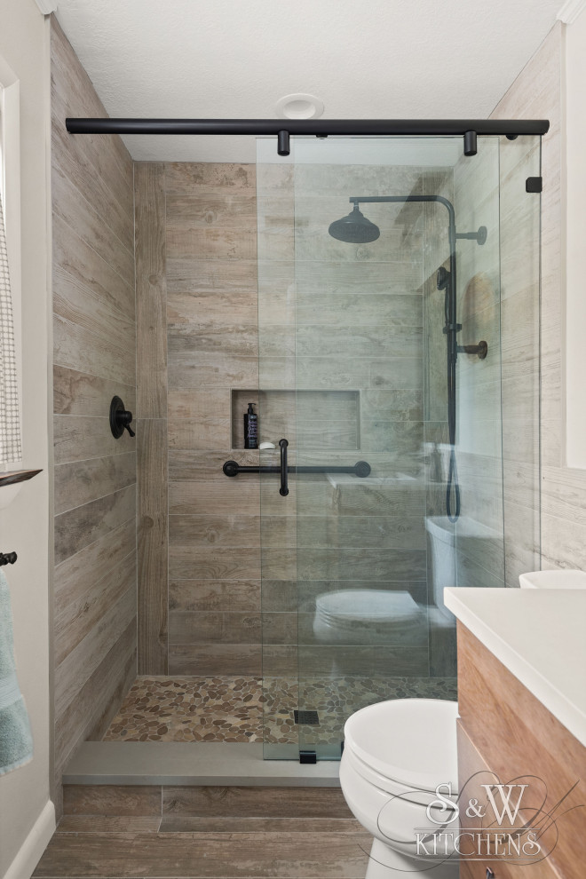 Idéer för ett mellanstort amerikanskt grå en-suite badrum, med luckor med infälld panel, skåp i mellenmörkt trä, en toalettstol med separat cisternkåpa, brun kakel, grå väggar, ett undermonterad handfat, bänkskiva i kvarts, brunt golv och dusch med skjutdörr