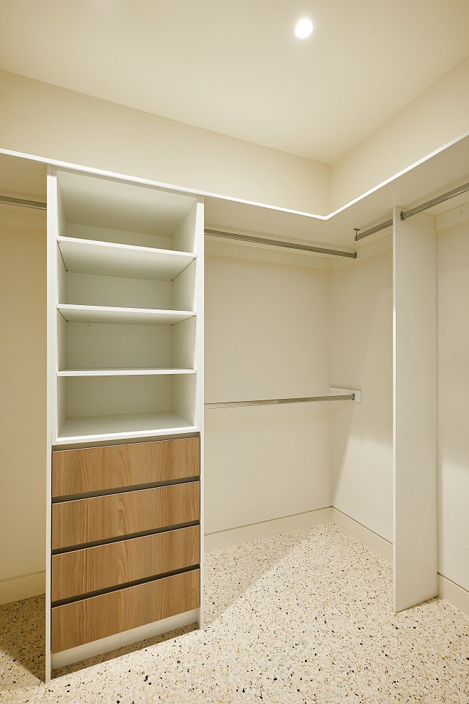 Immagine di una grande cabina armadio minimalista con ante lisce, ante in legno chiaro e pavimento in cemento