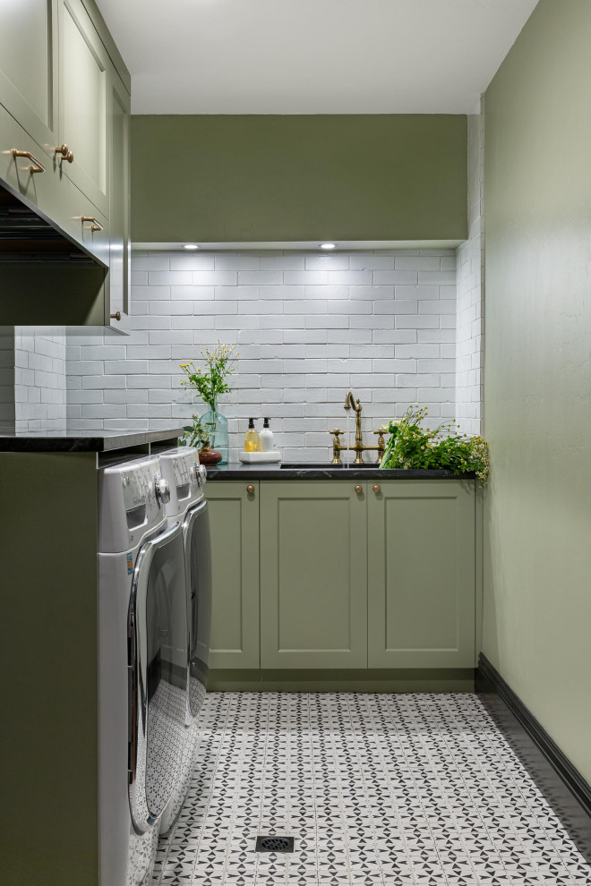 Mid-sized eclectic l-shaped laundry room in San Francisco with an integrated sink, shaker cabinets, green cabinets, soapstone benchtops, white splashback, brick splashback, green walls, terra-cotta floors, a side-by-side washer and dryer, multi-coloured floor and multi-coloured benchtop.