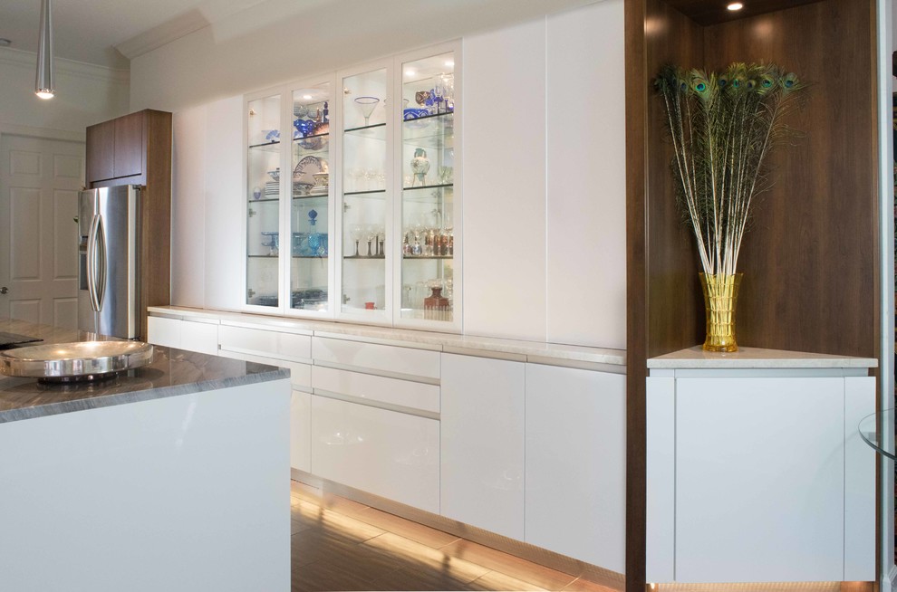 Eat-in kitchen - mid-sized contemporary l-shaped porcelain tile and brown floor eat-in kitchen idea in Miami with an integrated sink, flat-panel cabinets, white cabinets, granite countertops, white backsplash, stainless steel appliances, an island and subway tile backsplash