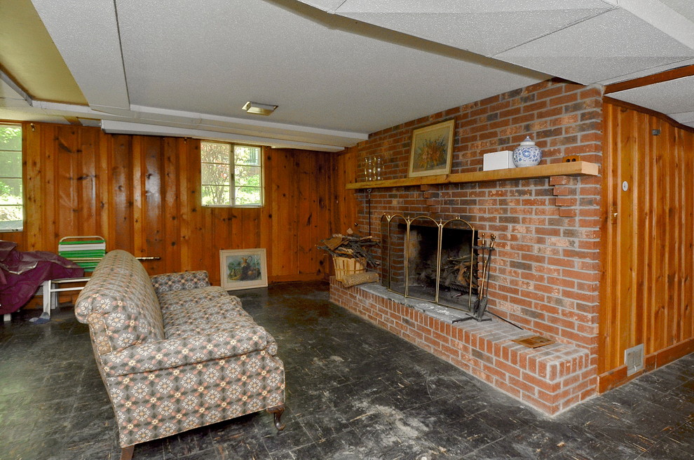 Example of a linoleum floor and black floor basement design with brown walls, a standard fireplace and a brick fireplace