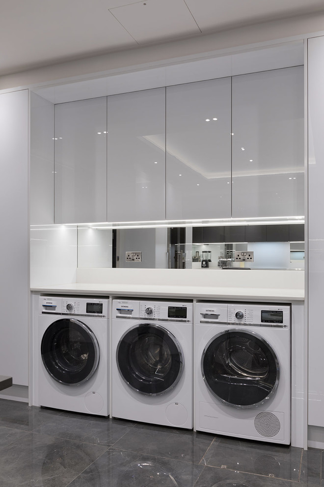 Inspiration for a large contemporary u-shaped laundry room in Hertfordshire with an undermount sink, flat-panel cabinets, grey cabinets, quartzite benchtops, mirror splashback, porcelain floors, grey floor and white benchtop.