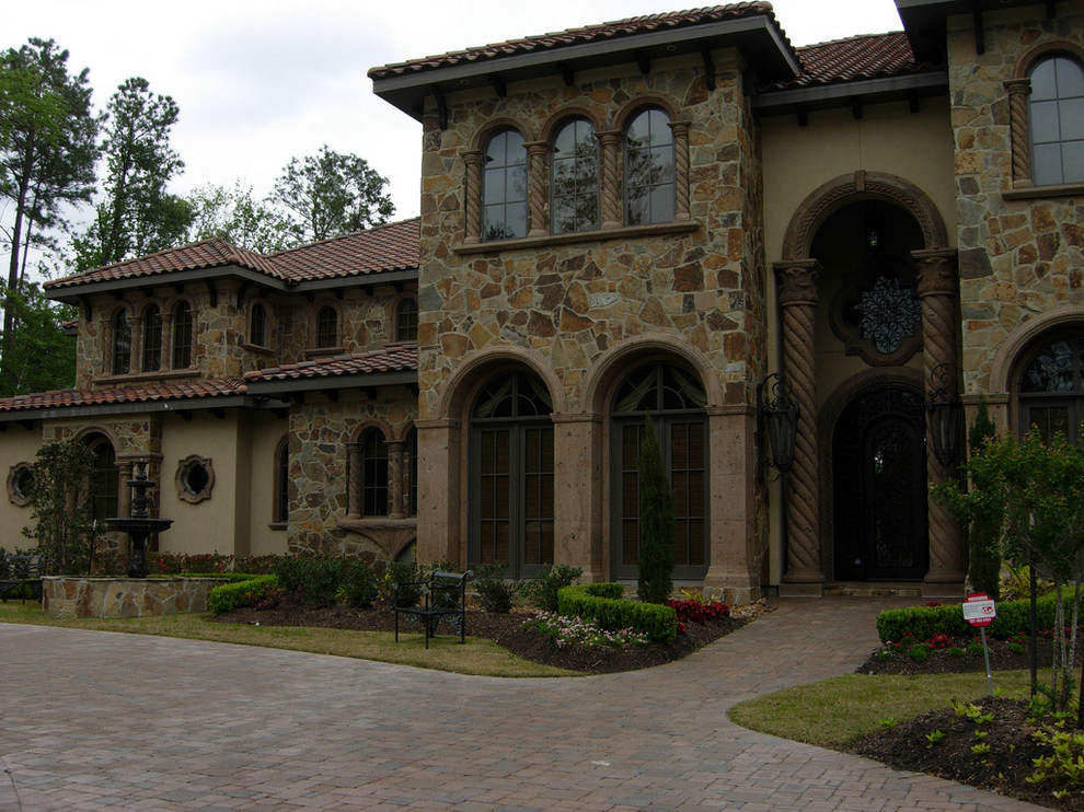 Design ideas for an expansive mediterranean two-storey brown exterior in Houston with mixed siding and a hip roof.
