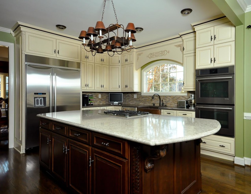 Mid-sized transitional l-shaped dark wood floor eat-in kitchen photo with raised-panel cabinets, white cabinets, multicolored backsplash, mosaic tile backsplash, stainless steel appliances, an island, a farmhouse sink and granite countertops