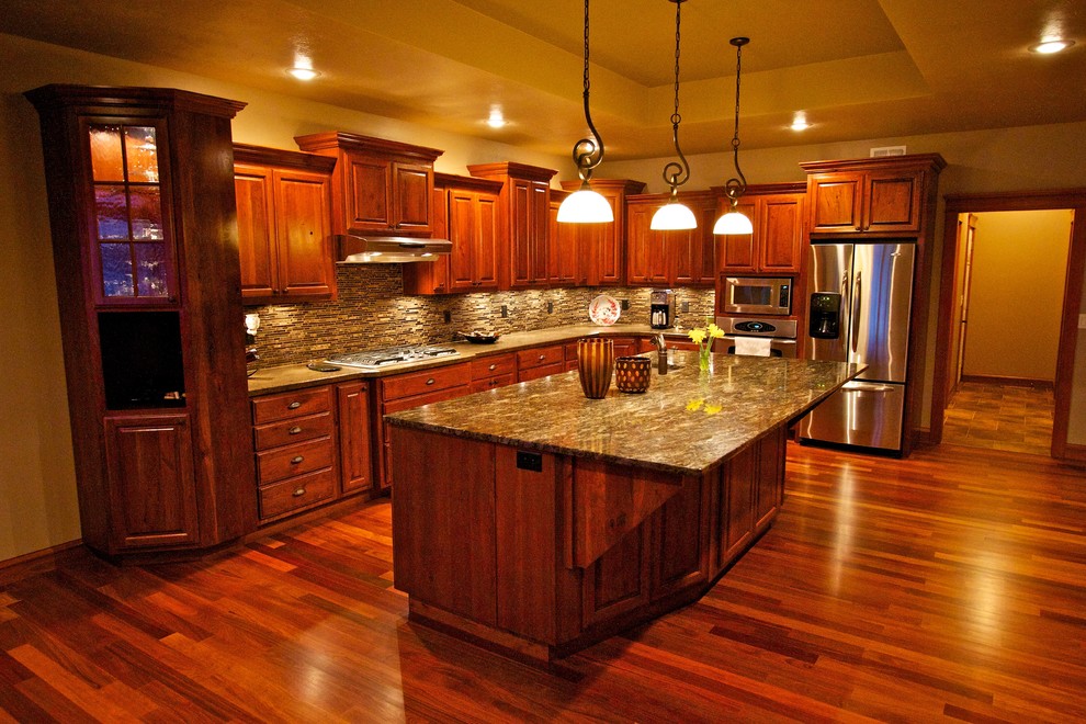 Open concept kitchen - large l-shaped medium tone wood floor open concept kitchen idea with an undermount sink, raised-panel cabinets, dark wood cabinets, multicolored backsplash, glass tile backsplash, stainless steel appliances and an island