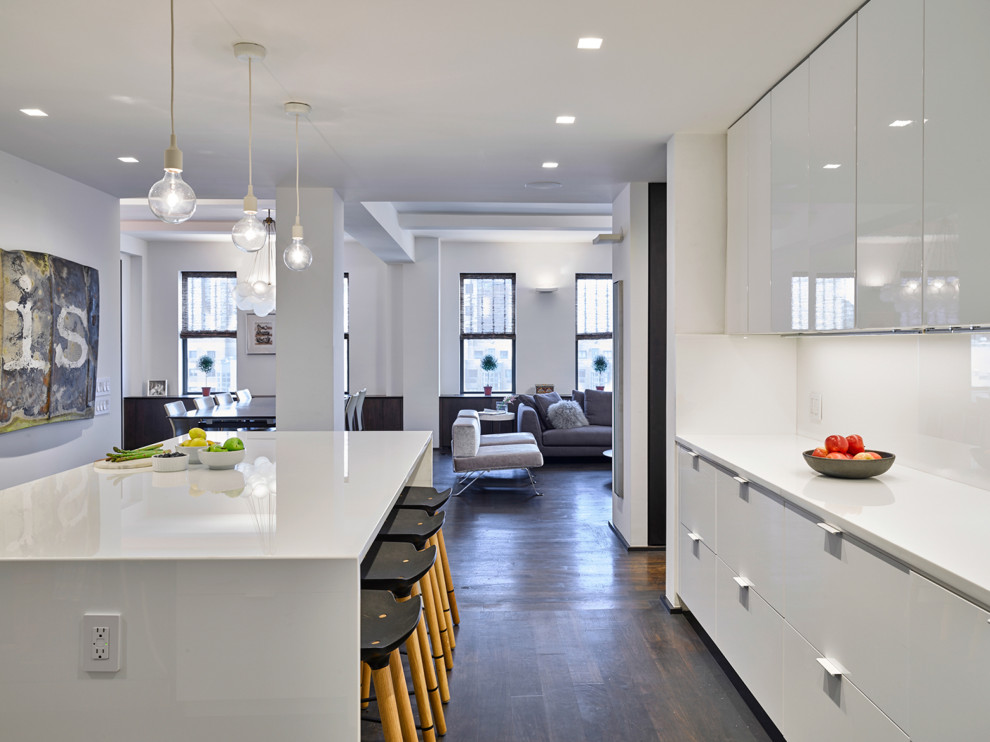 Large modern kitchen in New York with flat-panel cabinets, white cabinets, recycled glass countertops, white splashback, an island and white worktops.