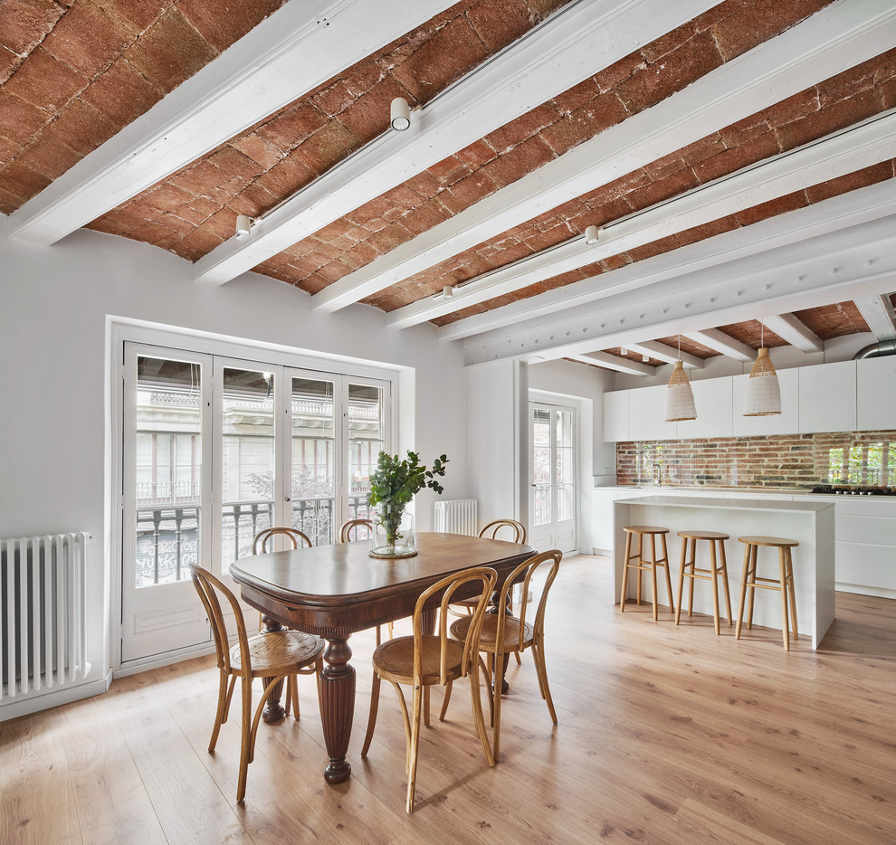 This is an example of a dining room in Barcelona with white walls, light hardwood floors and beige floor.