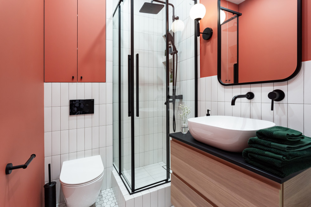 Modern inredning av ett svart svart badrum med dusch, med släta luckor, skåp i ljust trä, en hörndusch, en vägghängd toalettstol, vit kakel, röda väggar, ett fristående handfat, vitt golv och dusch med gångjärnsdörr