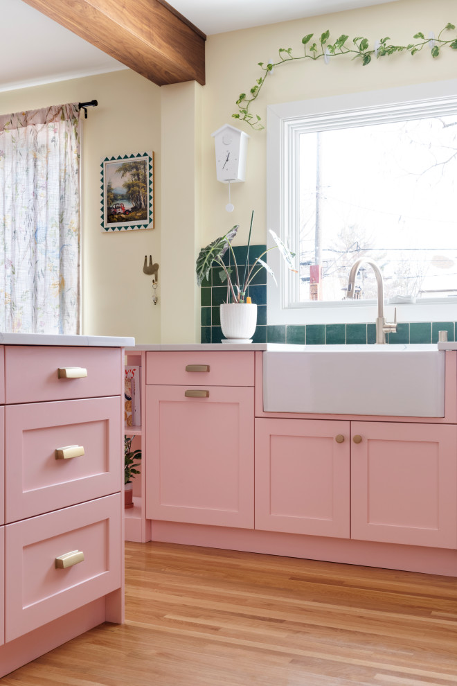 Inspiration for a mid-sized eclectic l-shaped eat-in kitchen in Minneapolis with a farmhouse sink, pink cabinets, quartz benchtops, green splashback, stainless steel appliances, light hardwood floors, with island, white benchtop, shaker cabinets, terra-cotta splashback and beige floor.