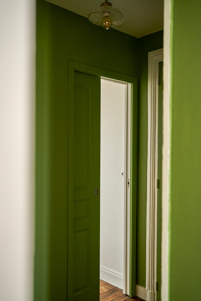 Foto på en liten 50 tals foajé, med gröna väggar, mörkt trägolv och brunt golv