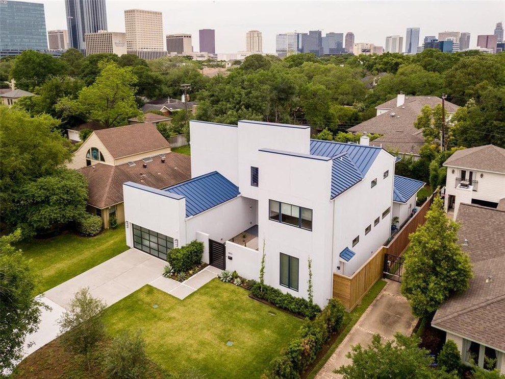 This is an example of a large contemporary two-storey stucco white house exterior in Houston with a gable roof and a shingle roof.