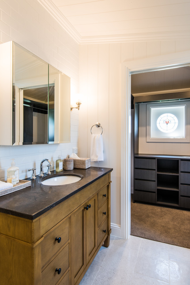 Mid-sized transitional 3/4 bathroom in Brisbane with shaker cabinets, medium wood cabinets, a drop-in tub, a shower/bathtub combo, a one-piece toilet, white tile, subway tile, white walls, ceramic floors, an undermount sink, marble benchtops, grey floor and a hinged shower door.