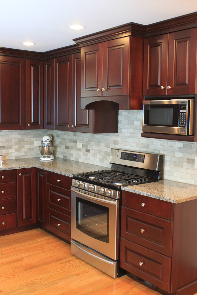 Eat-in kitchen - mid-sized transitional u-shaped laminate floor eat-in kitchen idea with an undermount sink, raised-panel cabinets, dark wood cabinets, quartz countertops, gray backsplash, porcelain backsplash, stainless steel appliances and no island