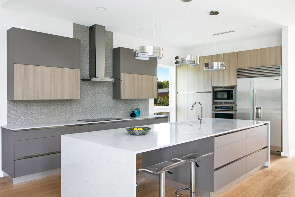 Mid-sized contemporary l-shaped kitchen in Tampa with an undermount sink, flat-panel cabinets, grey cabinets, quartz benchtops, grey splashback, stainless steel appliances, light hardwood floors, with island, white benchtop, mosaic tile splashback and beige floor.