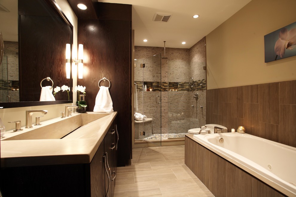 This is an example of a mid-sized contemporary master bathroom in New York with an integrated sink, flat-panel cabinets, dark wood cabinets, concrete benchtops, an alcove tub, a one-piece toilet, gray tile, ceramic tile, beige walls and ceramic floors.
