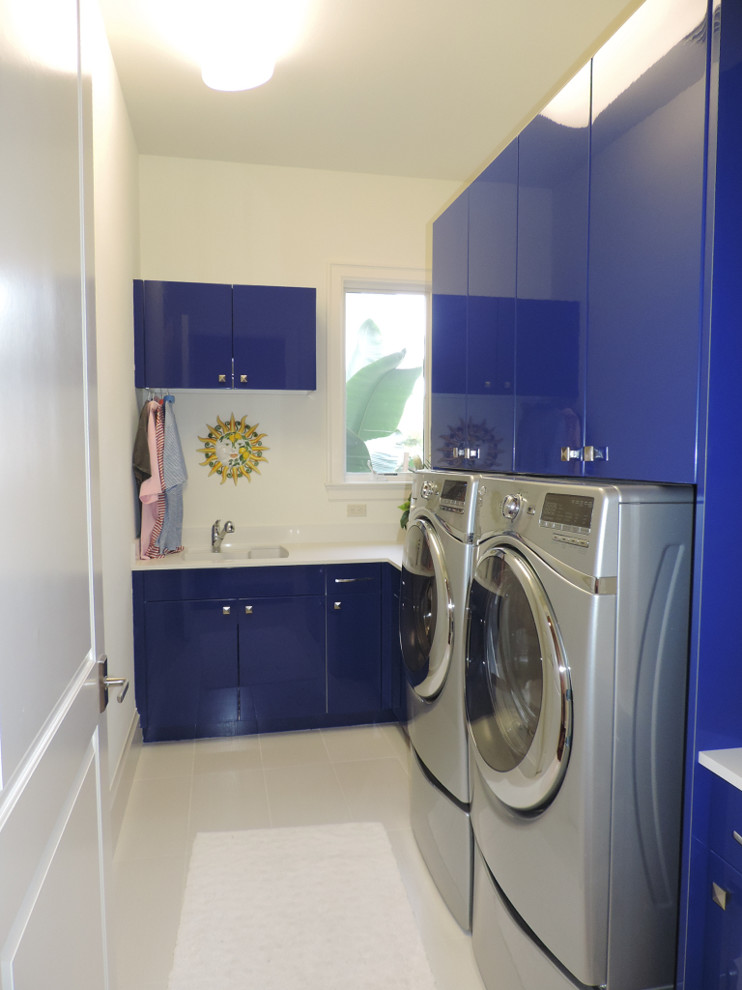 Design ideas for a mediterranean l-shaped laundry room in Miami with an undermount sink, flat-panel cabinets, blue cabinets, granite benchtops, beige walls, ceramic floors and a side-by-side washer and dryer.
