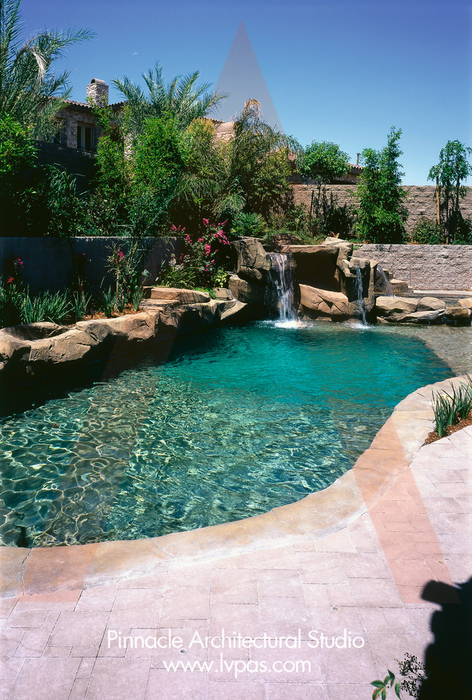 Design ideas for an expansive traditional front yard round lap pool in Las Vegas with a water feature and natural stone pavers.