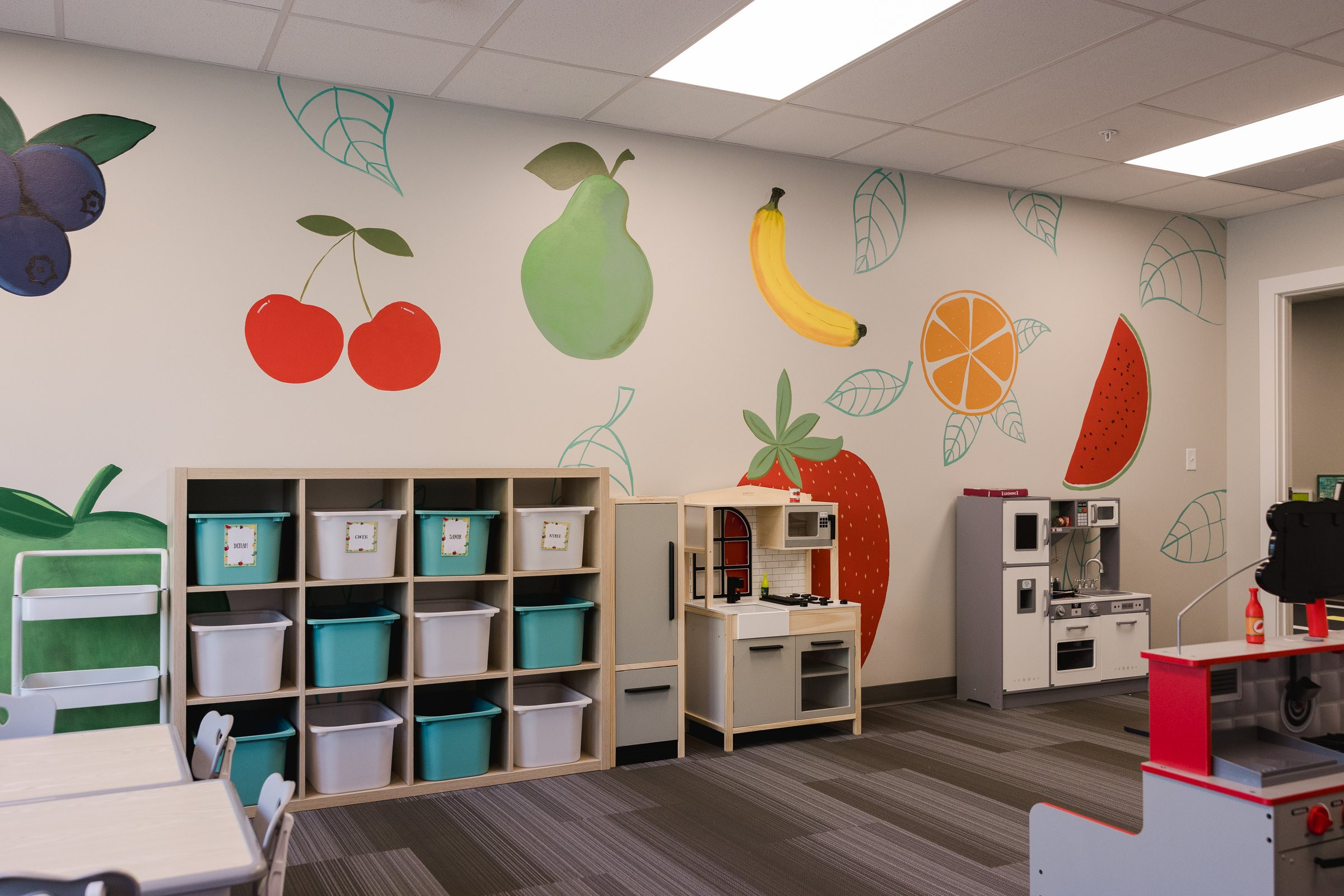Classroom with hand-painted fruit mural and play kitchens, Galliant Autism Center Omaha