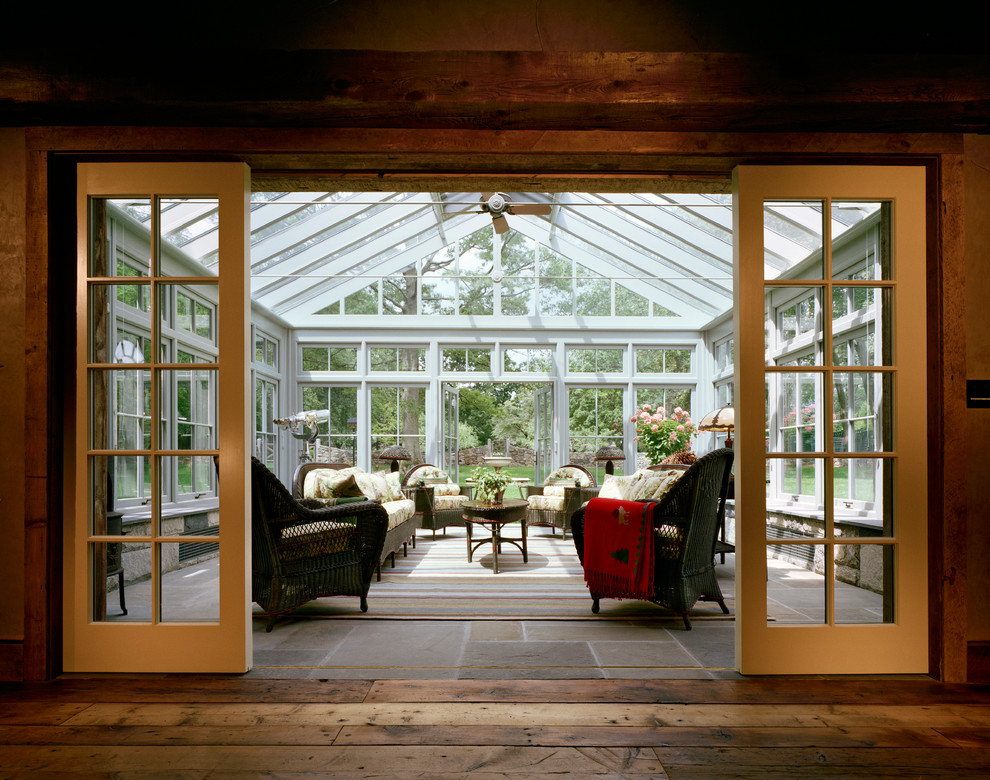 This is an example of a large country sunroom in New York with slate floors, no fireplace and a glass ceiling.