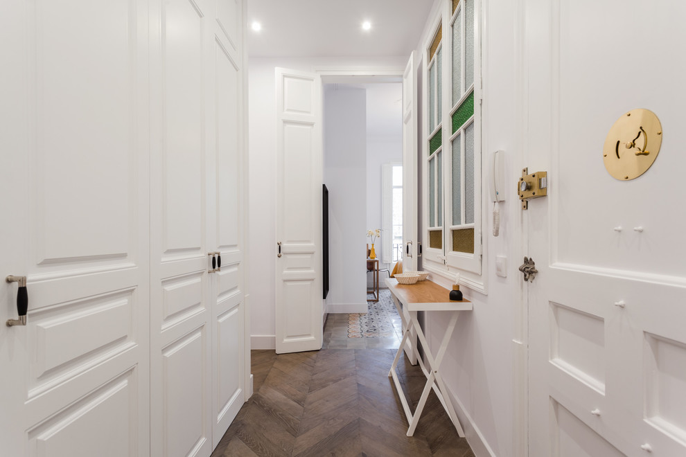 This is an example of a traditional hallway in Barcelona with white walls, dark hardwood floors and brown floor.