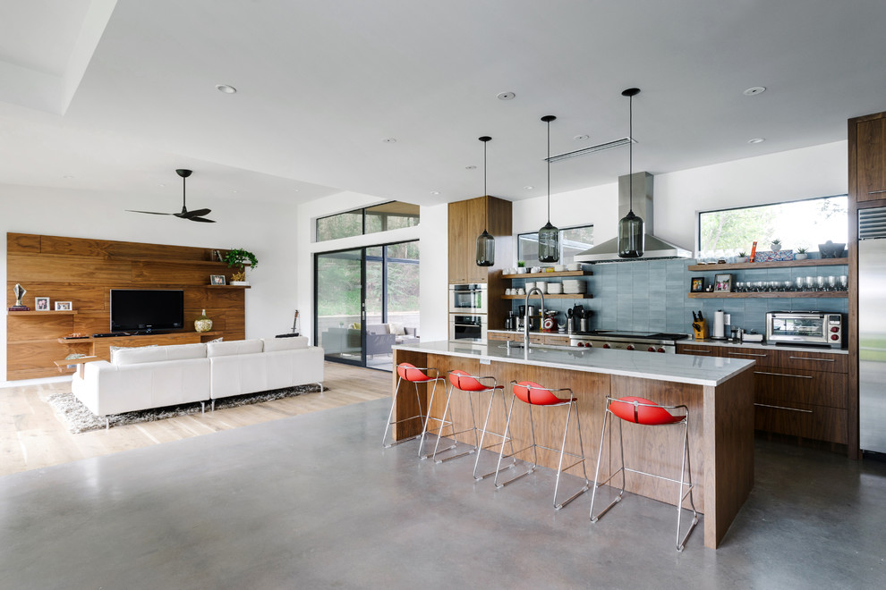 Mid-sized modern galley open plan kitchen in Austin with an undermount sink, flat-panel cabinets, dark wood cabinets, marble benchtops, blue splashback, stone tile splashback, stainless steel appliances, concrete floors, with island and grey floor.
