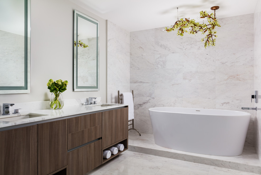 Photo of a large contemporary master bathroom in Miami with flat-panel cabinets, dark wood cabinets, a freestanding tub, an alcove shower, a one-piece toilet, white tile, marble, white walls, marble floors, an undermount sink, marble benchtops, white floor, a hinged shower door and white benchtops.
