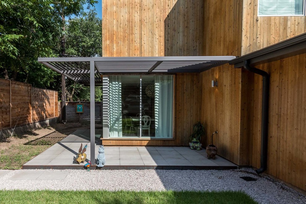 Photo of a mid-sized modern front yard verandah in Austin with concrete pavers and an awning.