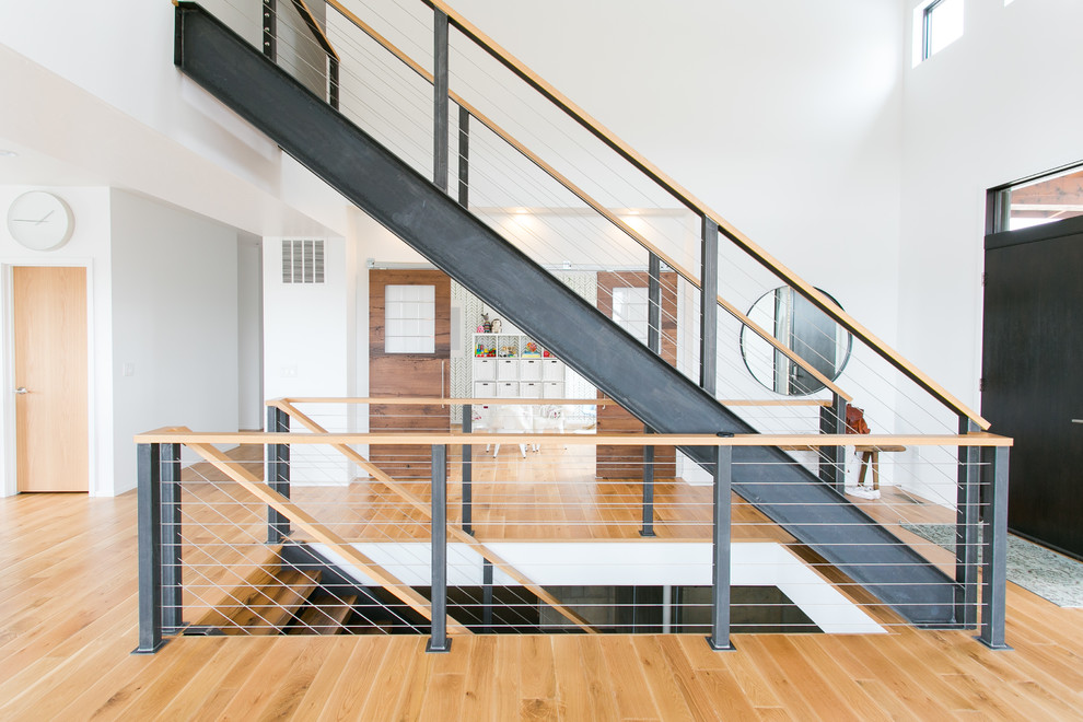 Photo of a large contemporary straight staircase in Cleveland with cable railing.