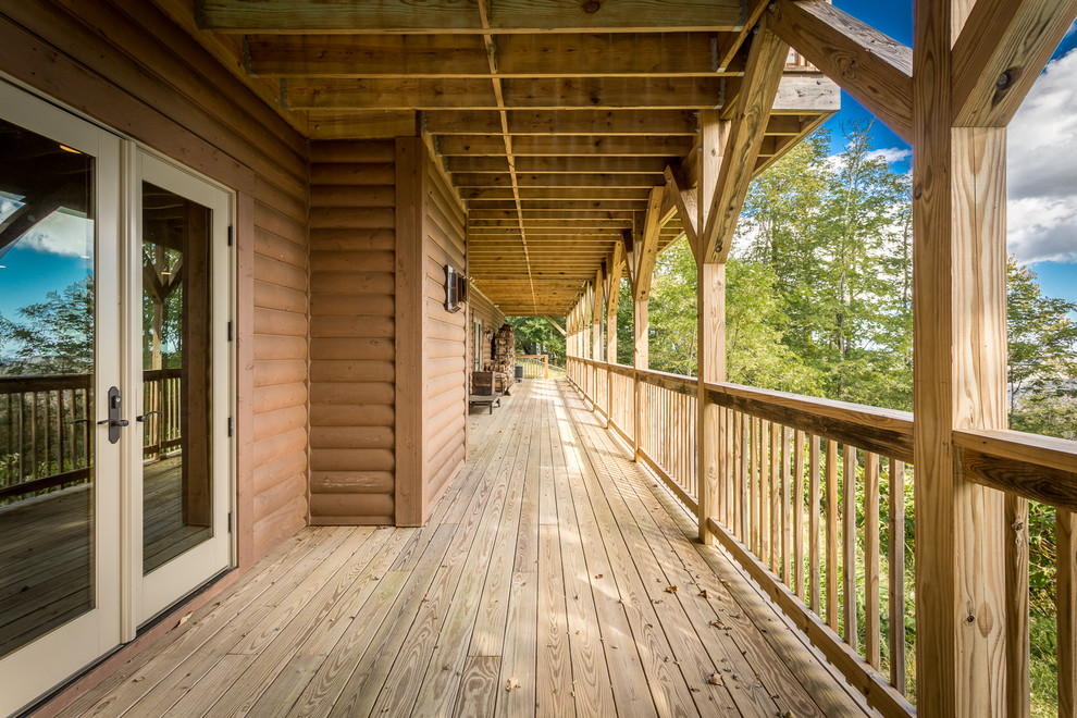 Deck - huge rustic backyard deck idea in Charlotte with a roof extension