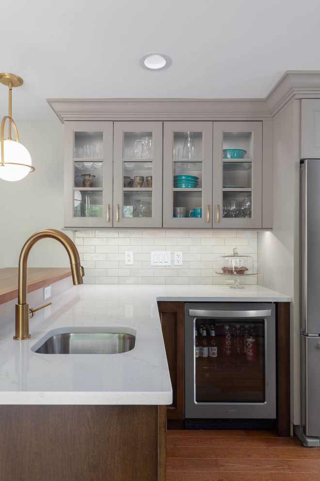 Transitional medium tone wood floor kitchen photo with quartz countertops, quartz backsplash, stainless steel appliances and white countertops