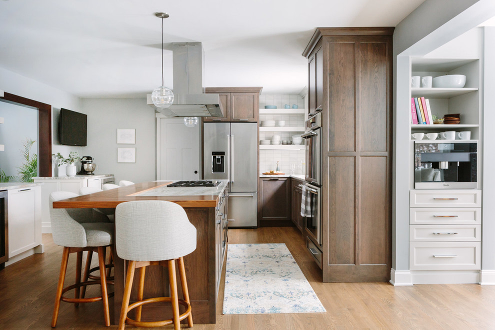 Transitional u-shaped dark wood floor and brown floor eat-in kitchen photo in Chicago with an undermount sink, shaker cabinets, dark wood cabinets, marble countertops, beige backsplash, stainless steel appliances, an island and beige countertops