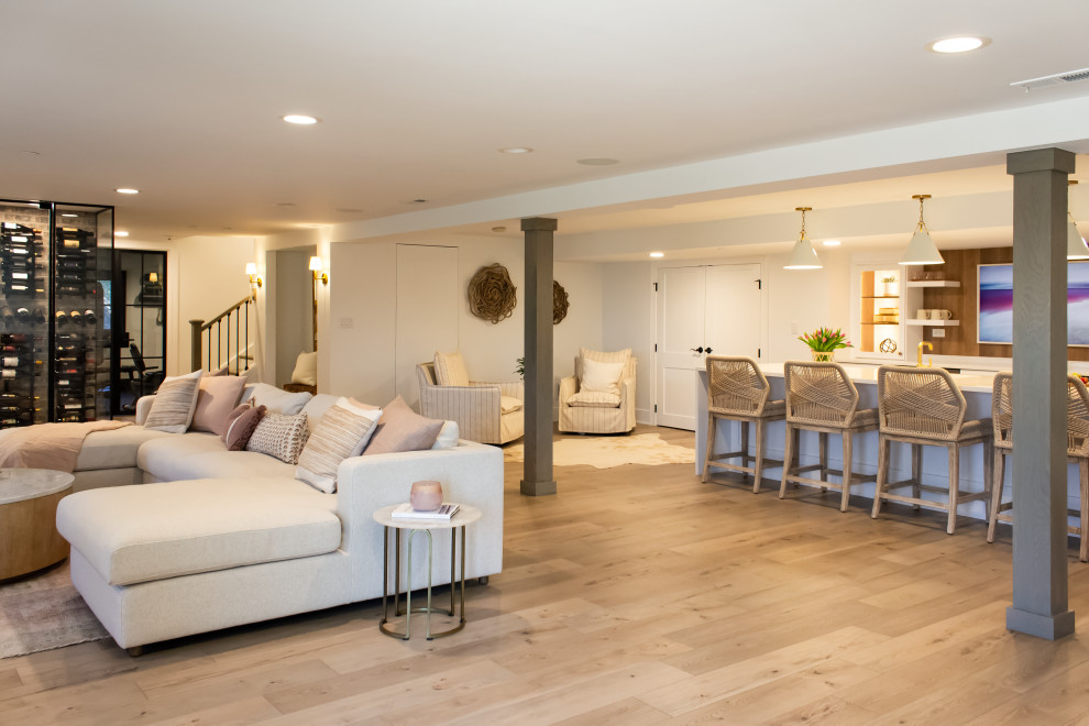 This is an example of a large transitional walk-out basement in Chicago with a home bar, laminate floors, a standard fireplace and a brick fireplace surround.