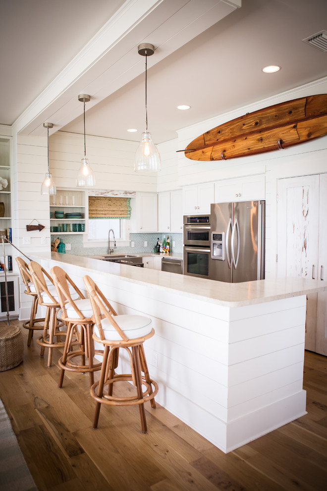 Inspiration for a beach style l-shaped open plan kitchen in Other with stainless steel appliances and white cabinets.