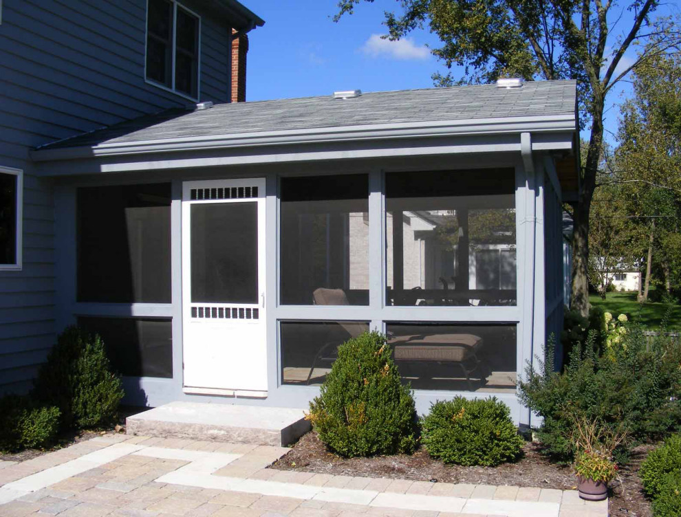 Foto di un portico chic di medie dimensioni e dietro casa con un portico chiuso, pavimentazioni in pietra naturale, un tetto a sbalzo e parapetto in vetro