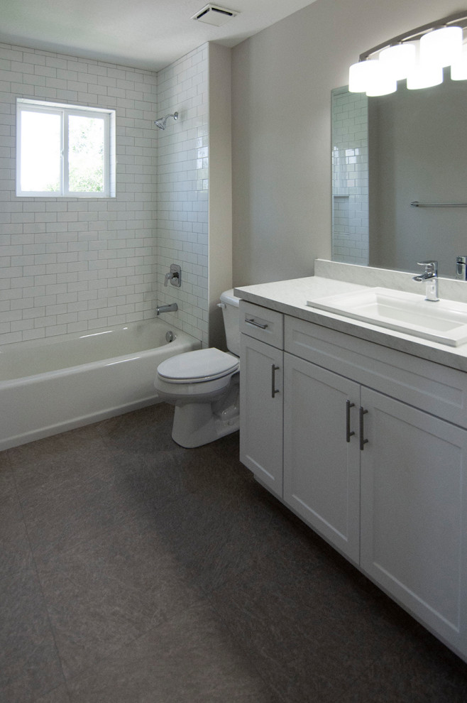 Foto på ett vintage vit en-suite badrum, med vit kakel, luckor med infälld panel, vita skåp, ett badkar i en alkov, en dusch/badkar-kombination, tunnelbanekakel, beige väggar, vinylgolv, ett nedsänkt handfat, svart golv och dusch med duschdraperi