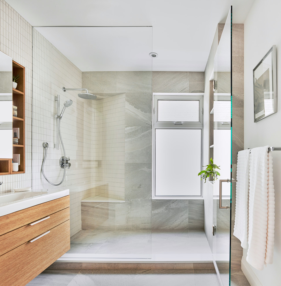 Mid-sized 3/4 bathroom in Toronto with light wood cabinets, an alcove shower, multi-coloured tile, multi-coloured walls, grey floor, a hinged shower door and glass-front cabinets.