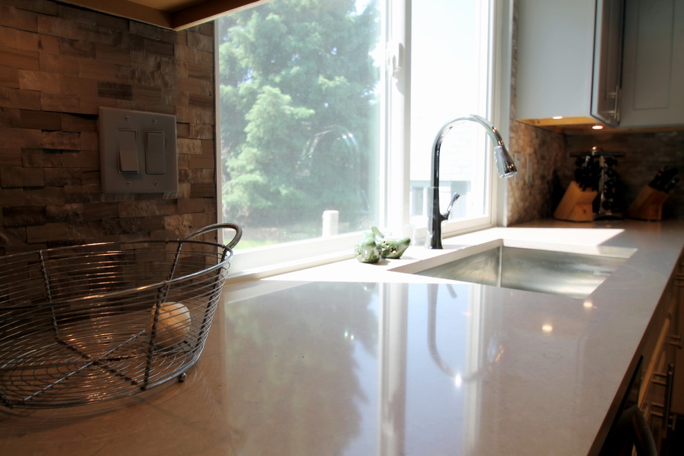 Eat-in kitchen - large transitional l-shaped medium tone wood floor eat-in kitchen idea in Denver with an undermount sink, shaker cabinets, gray cabinets, quartz countertops, gray backsplash, stone tile backsplash, stainless steel appliances and an island